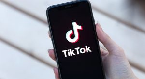 a person with long nails holding an iPhone which is running TikTok