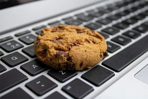An image featuring a laptop and a cookie on top of it representing web cookies