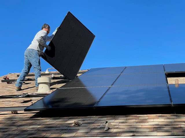 man installing solar panels on roof
