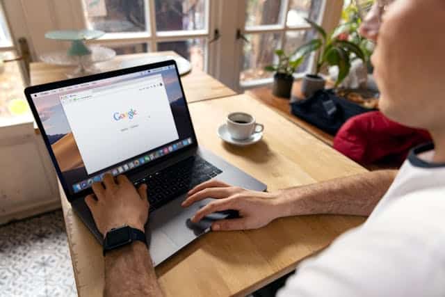 Person-Using-Macbook-Pro-on-Brown-Wooden-Table